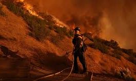 Firefighters raced to contain the frontiers of two Los Angeles wildfires that burned for the sixth straight day on Sunday, taking advantage of a brief respite in hazardous conditions before high winds were expected to fan the flames anew. At least 24 people have died in what California Governor Gavin Newsom said could be the most devastating natural disaster in U.S. history, one that has destroyed thousands of homes and forced 100,000 people to evacuate. Advertisement · Scroll to continue Flames have reduced whole neighborhoods to smoldering ruins, leveling the homes of the rich and famous and ordinary folk alike, and leaving an apocalyptic landscape. Officials said at least 12,300 structures have been damaged or destroyed. "L.A. County had another night of unimaginable terror and heartbreak," Los Angeles County Supervisor Lindsey Horvath said. Aerial firefighters, some of them scooping water out of the Pacific Ocean, dropped water and retardant while land crews with hand tools and hoses held the line of the Palisades Fire as it encroached on the upscale Brentwood section and other populated areas of Los Angeles. Advertisement · Scroll to continue That fire on the western side of town has consumed 23,713 acres (96 sq km) or 37 square miles and stood at 13% contained, a figure representing the percentage of the fire's perimeter that firefighters have under control. The Eaton Fire in the foothills east of Los Angeles scorched another 14,117 acres (57 sq km) or 22 square miles - itself nearly the size of Manhattan - and firefighters increased the containment to 27%, up from 15% a day earlier. North of the city, the Hurst Fire was 89% contained, and three other fires that had ravaged other parts of the county were now 100% contained, the California Department of Forestry and Fire Protection (Cal Fire) reported, though areas within the containment lines may still be burning. SEVERE WINDS RETURN Firefighters got a temporary break from the weather this weekend as Santa Ana winds, which reached hurricane force earlier in the week, finally eased. The dry winds originating from the inland deserts had fanned flames and blew embers up to 2 miles (3 km) ahead of the front lines. But, in an area that has not received any rain of note since April, the National Weather Service forecast Santa Ana winds of up to 50 to 70 miles per hour (80 to 112 kph) would resume on Sunday night (U.S. West Coast time) and last through Wednesday. Officials warned the entire Los Angeles County population of nearly 10 million that anyone may be ordered to evacuate from the flames and toxic smoke. By Sunday, more than 100,000 people in Los Angeles County had been ordered to evacuate - down from a previous high of more than 150,000 - while another 87,000 faced evacuation warnings. "These winds combined with low relative humidities and low fuel moistures will keep the fire threat in all of Los Angeles County very high," Los Angeles County Fire Chief Anthony Marrone told a press conference, adding that evacuated areas may not be reopened until red flag conditions are lifted on Thursday. Even so, schools except some in mandatory evacuation zones would reopen on Monday, after closing for all 429,000 students in the Los Angeles Unified School District on Thursday and Friday, Superintendent Alberto Carvalho announced. Item 1 of 18 Firefighters work to clear a firebreak as the Palisades Fire, one of several simultaneous blazes that have ripped across Los Angeles County, burns in Mandeville Canyon, a neighborhood of Los Angeles, California, U.S., January 12, 2025. REUTERS/Ringo Chiu [1/18]Firefighters work to clear a firebreak as the Palisades Fire, one of several simultaneous blazes that have ripped across Los Angeles County, burns in Mandeville Canyon, a neighborhood of Los Angeles, California, U.S., January 12, 2025. REUTERS/Ringo Chiu Purchase Licensing Rights, opens new tab Newsom told NBC News the fires were likely to be the worst natural disaster in U.S. history "in terms of just the costs associated with it." The Los Angeles County Medical Examiner reported 24 deaths from the fires. Private forecaster AccuWeather has estimated the damage and economic loss at $135 billion to $150 billion. To help expedite the monumental rebuilding effort ahead, Newsom signed an executive order on Sunday temporarily suspending environmental regulations for destroyed homes and businesses. Active duty military personnel are ready to support the firefighting effort, FEMA Administrator Deanne Criswell said in a series of Sunday television interviews, adding the agency has urged residents to begin filing for disaster relief. Firefighters from seven states, Canada and Mexico have already converged on the Los Angeles area to help fire departments from around the state. HIGH ANXIETY Hundreds of people displaced by the fires attended mass at the St. Monica Catholic Church in Santa Monica on Sunday, including parishioners whose churches were destroyed. Kathleen McRoskey, who attended mass regularly at Pacific Palisades' ruined Corpus Christi church for over 40 years, said she was grateful to St. Monica for opening its doors to those who lost their homes and place of worship. "It was the first offer of support that would heal us spiritually and physically and emotionally," she said. In Altadena on the edge of the Eaton Fire, Tristin Perez said he never left his home, defying police orders to evacuate as the fire raced down the hillside. Instead, Perez insisted on trying to save his property and his neighbors' homes. "Your front yard is on fire, palm trees lit up – it looked like something out of a movie," Perez told Reuters in an interview in his driveway. "I did everything I could to stop the line and save my house, help save their houses." His one-story yellow duplex survived. So did two more homes next door. Across the street, entire houses burned to the ground. "A lot of these areas still look like they were hit by a bomb. There are live electrical wires, gas lines and other hazards," said Los Angeles County Sheriff Robert Luna. Zuzana Korda was evacuated from her home in the Fernwood neighborhood in Topanga, northwest of Los Angeles. Speaking outside a temporary assistance office at the West Hollywood Public Library, she said her landlord told her the family home was still standing, but she was anxious. "We've left everything behind. We have no insurance," Korda said. "We stand to lose everything."